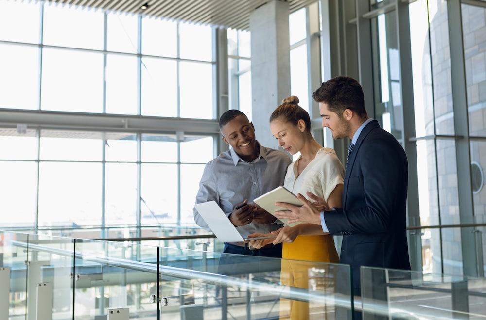 Business colleagues standing in modern office lobby using computers